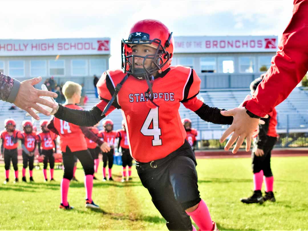 Holly Stampede Youth Football Player high-fiving coaches Holly, Michigan